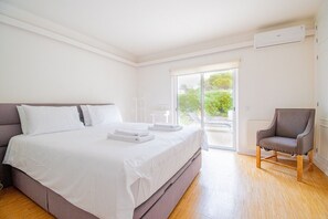 Ein Schlafzimmer mit einem großen Bett, einem Sessel und einer Glastür, die auf einen Balkon führt.