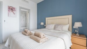 A bedroom with a bed, two bedside tables, a nightstand, a window, and a door. - Apartment '203 Arruzafa Sea View' with Sea View, Wi-Fi and Air Conditioning (Las Lagunas de Mijas)