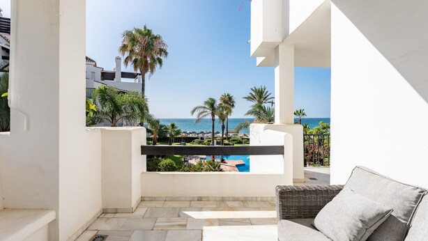 A balcony with a view of the sea, a pool, and a white building. - Apartment '203 Arruzafa Sea View' with Sea View, Wi-Fi and Air Conditioning (Las Lagunas de Mijas)