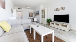 A modern living room with a sofa, a coffee table, a TV, and a cabinet. - Apartment '203 Arruzafa Sea View' with Sea View, Wi-Fi and Air Conditioning (Las Lagunas de Mijas)