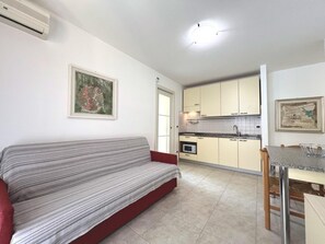 A compact living space with a sofa, kitchenette, and dining area. - Spacious and Comfortable Holiday Home in Grado (Grado)