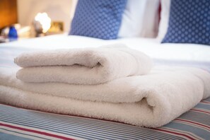 A neatly folded white towel on a striped bedspread. - Imperial Lodge (Great Yarmouth)