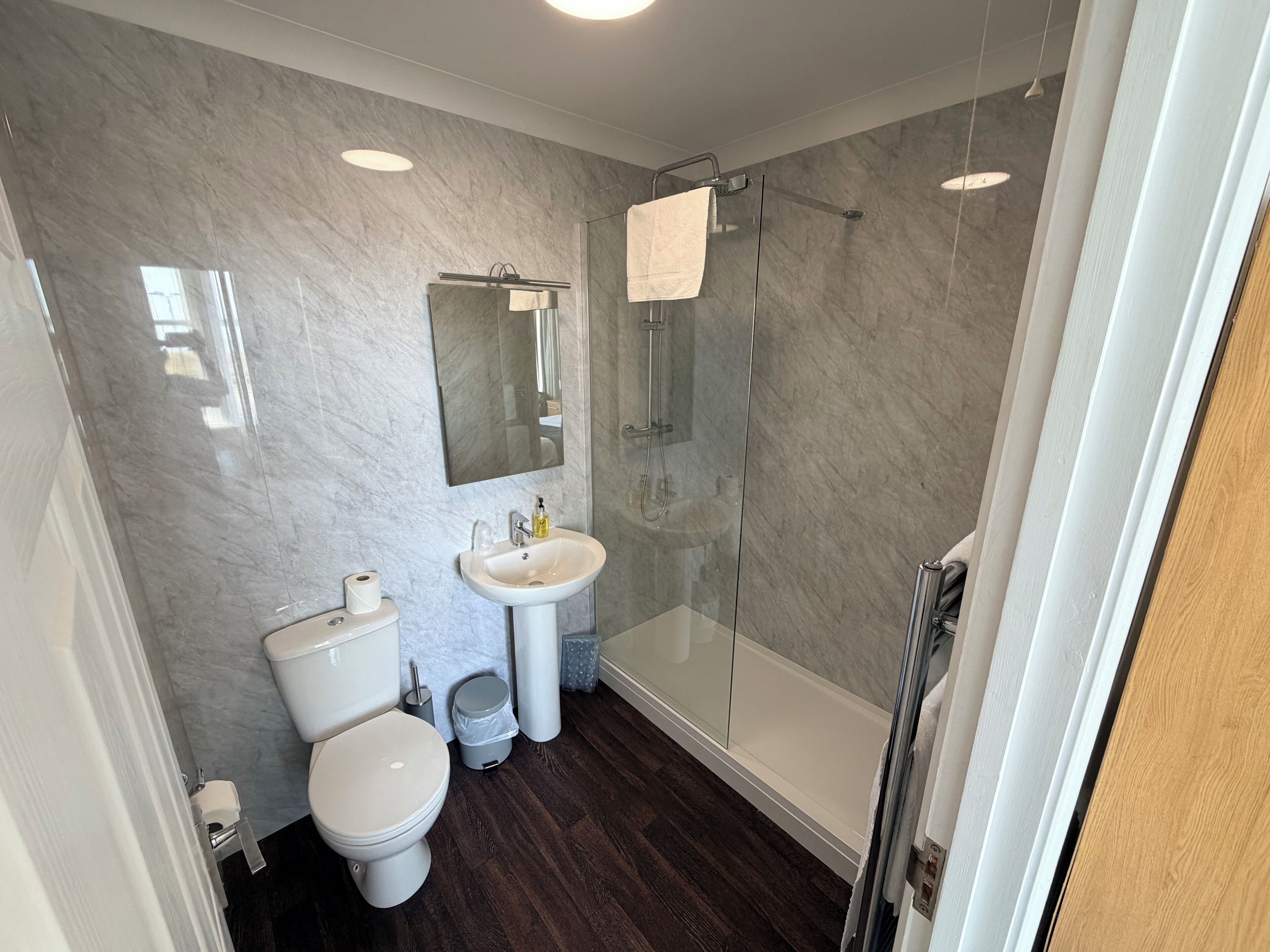 Een badkamer met toilet, wastafel en een douchecabine met glazen wanden.