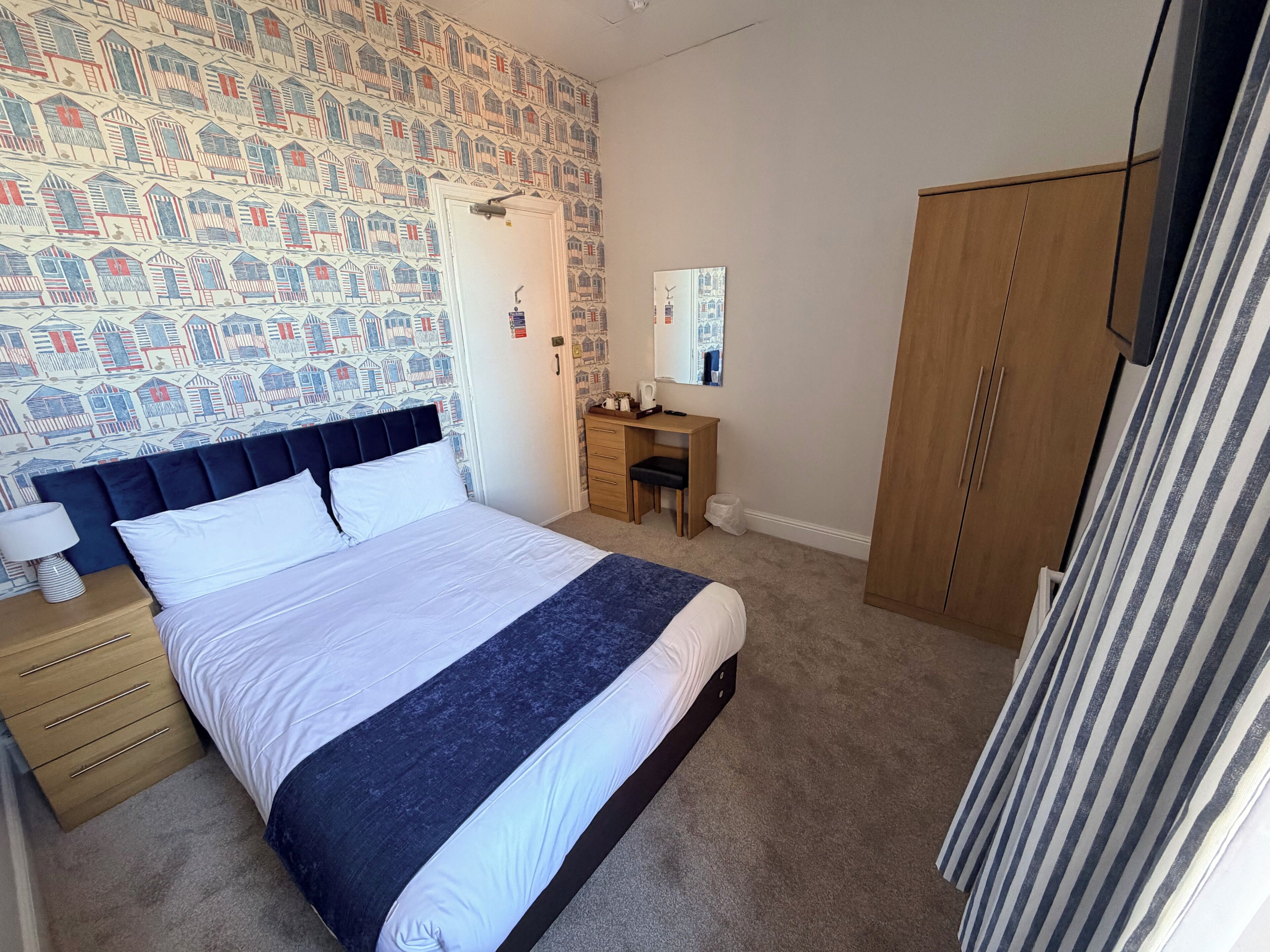 Un dormitorio con cama, escritorio, armario y pared con diseño.