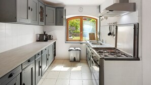A kitchen with grey cabinets, a stainless steel refrigerator, a gas stove, and a window with a view of greenery. - Holiday Home 'Maison En Cevennes' with Mountain View, Private Pool and Private Terrace (L'Estréchure)