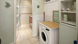 A laundry area with a washing machine, a drying rack, and a shelf with toiletries. - Holiday Home 'Maison En Cevennes' with Mountain View, Private Pool and Private Terrace (L'Estréchure)