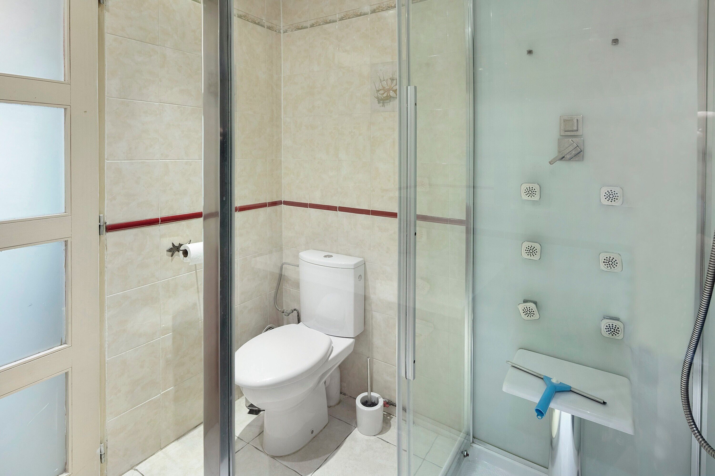 A bathroom with a glass-enclosed shower, a toilet, and a sink with a handheld showerhead.