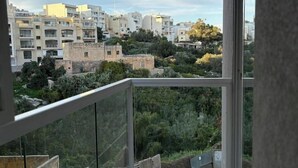 En balkong med utsikt över en stadsbild, inklusive byggnader och grönområden.