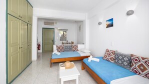 Une chambre d’hôtel de taille modeste, comprenant deux lits simples, une petite table et une armoire.