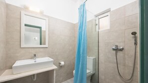 Une salle de bain équipée d’un lavabo, de toilettes, d’une douche et d’un miroir.