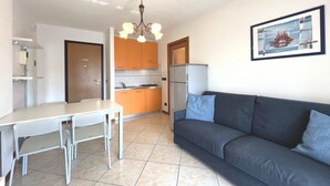 A compact living space with a kitchenette, a dining area, and a sofa. - Cozy Holiday Escape Apartment With City View (Grado)