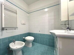 A bathroom with a bidet, toilet, and sink. - Cozy Holiday Escape Apartment With City View (Grado)