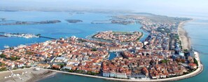 An aerial view of a coastal city with a dense urban area, a marina, and a beach. - Cozy Holiday Escape Apartment With City View (Grado)