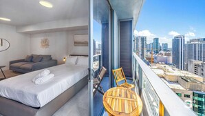 Habitación de hotel moderna con una cama grande, un sofá y un balcón con vistas al horizonte de la ciudad.