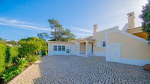 A house with a cobblestone driveway, a small garden, and a white exterior. - Vivenda Liberdade in Carvoeiro (Lagoa)