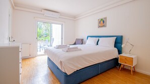 A bedroom with a bed, a nightstand, a radiator, and a door leading to an outdoor area. - Vivenda Liberdade in Carvoeiro (Lagoa)