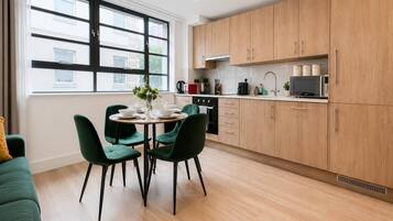 A modern kitchen with wooden cabinets, a dining table with chairs, and a window with a view of buildings.