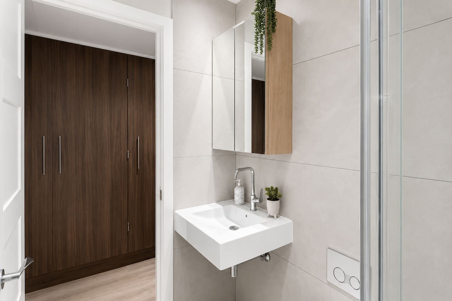 Un bagno moderno con un lavandino bianco, uno specchio e un armadietto in legno.