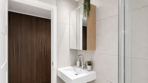 Un baño moderno con un lavamanos blanco, un espejo y un mueble de madera.