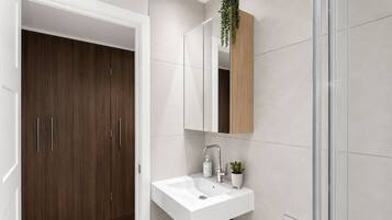 Un bagno moderno con un lavandino bianco, uno specchio e un armadietto in legno.