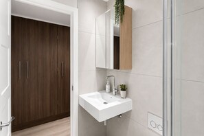 A modern bathroom with a white sink, a mirror, and a wooden cabinet. - Furnished Studio Apt Near Regent's park + ac/lift (London)