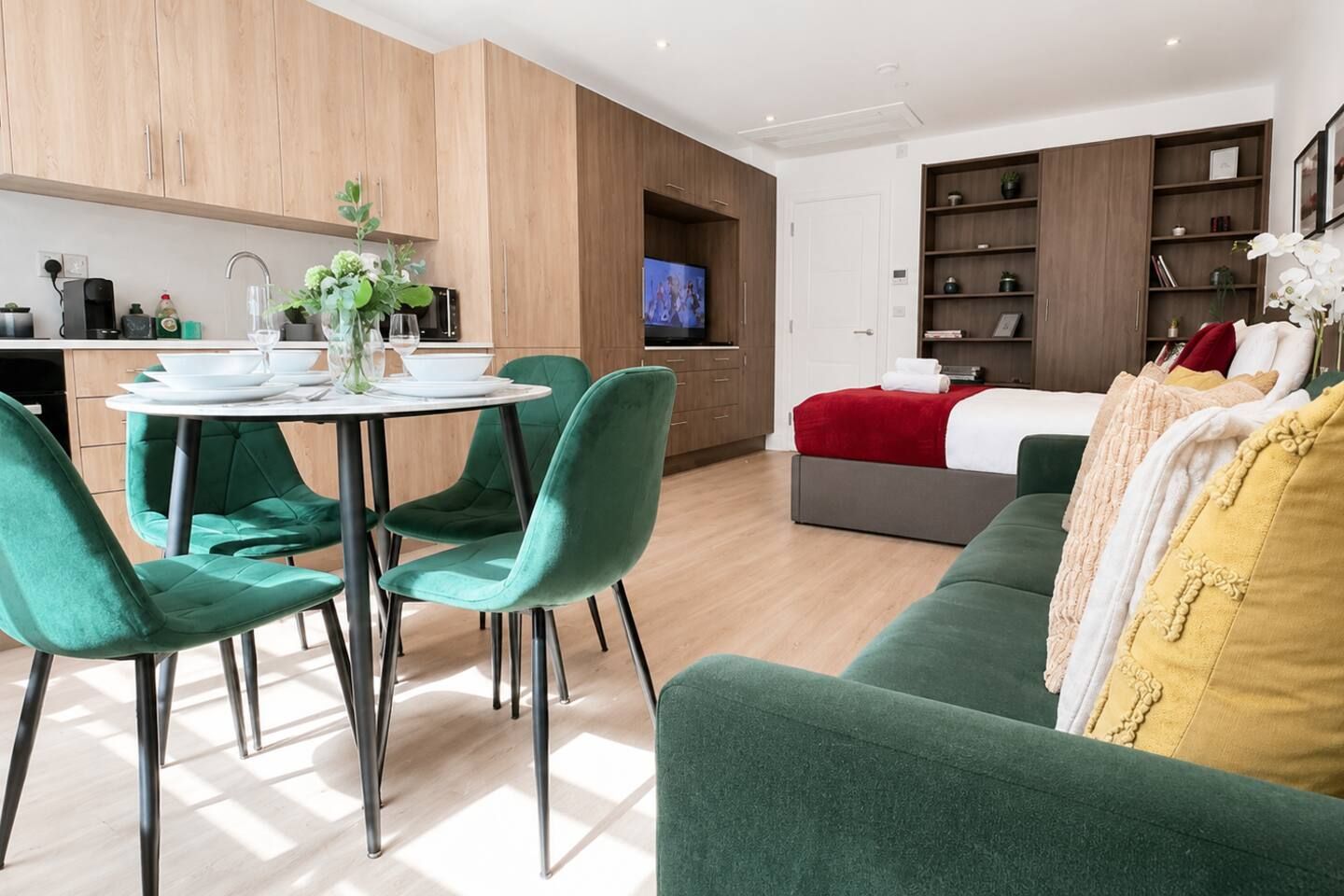 A modern living space with a dining area, a sofa, and a TV in the background.