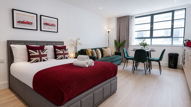 Quarto de hotel moderno com uma cama grande, um sofá verde, área de refeições e uma janela com cortinas.