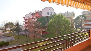 A residential building with balconies, a garden area, and a view of other buildings. - Cozy Flat for Four Guests Just Steps From the sea (Grado)