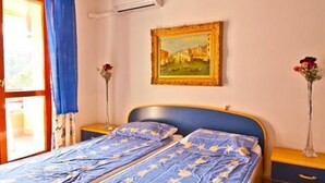 A bedroom with a bed, a painting, and a vase with flowers. - Cozy Flat for Four Guests Just Steps From the sea (Grado)