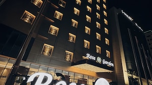Un hotel con una facciata moderna, finestre illuminate e un'imponente insegna con la scritta 'Rose Garden'.
