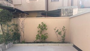 A paved courtyard with a low wall, some greenery, and a drainage grate. - Sea Breeze Holiday Villa in Grado (Grado)