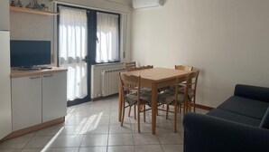 A compact kitchen with a dining table and chairs, a TV, and a sofa. - Sea Breeze Holiday Villa in Grado (Grado)