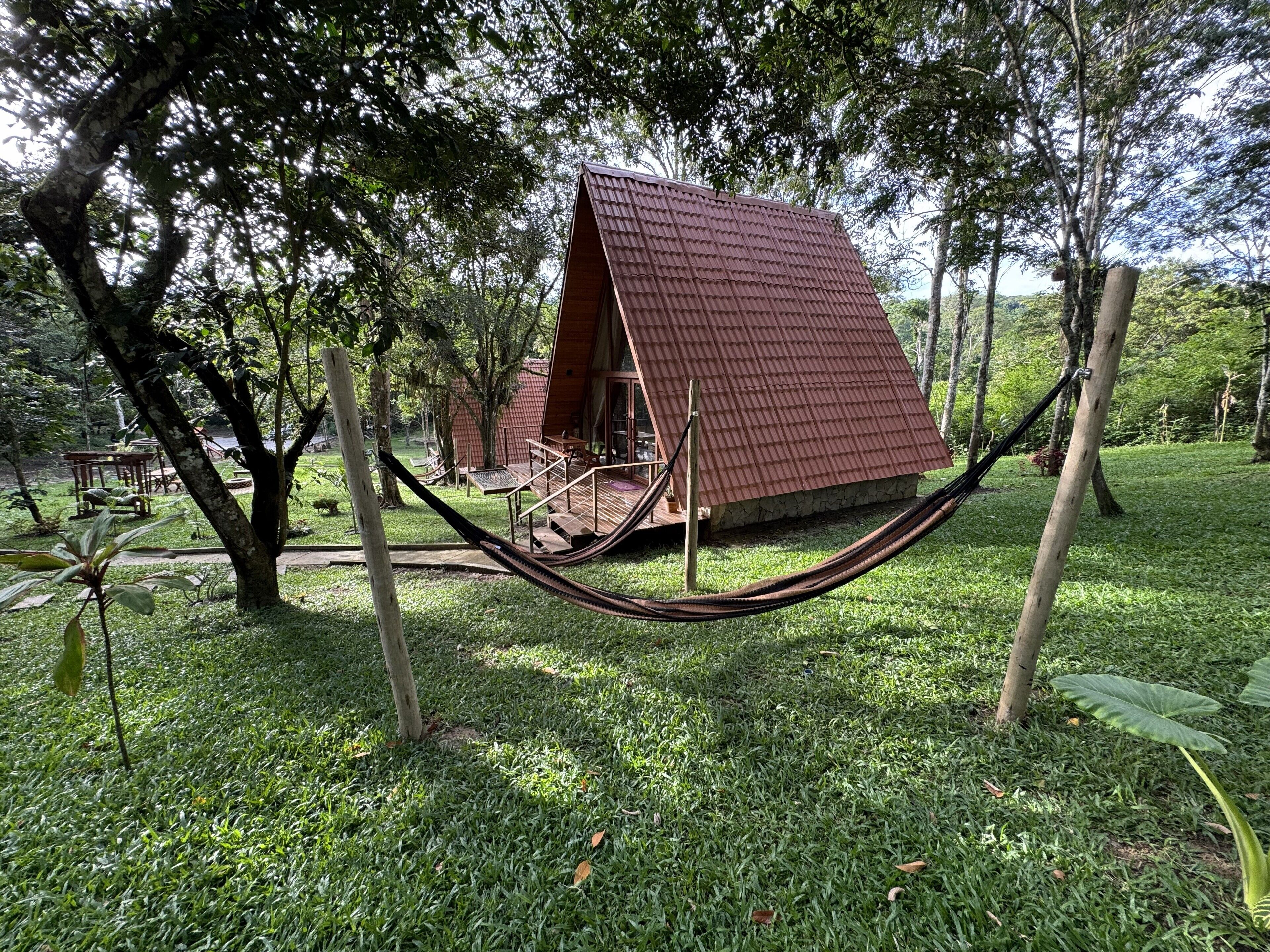 A hammock in a grassy area with a red-roofed building in the background.