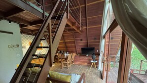 Un intérieur en bois avec un escalier, un coin repas et un téléviseur.