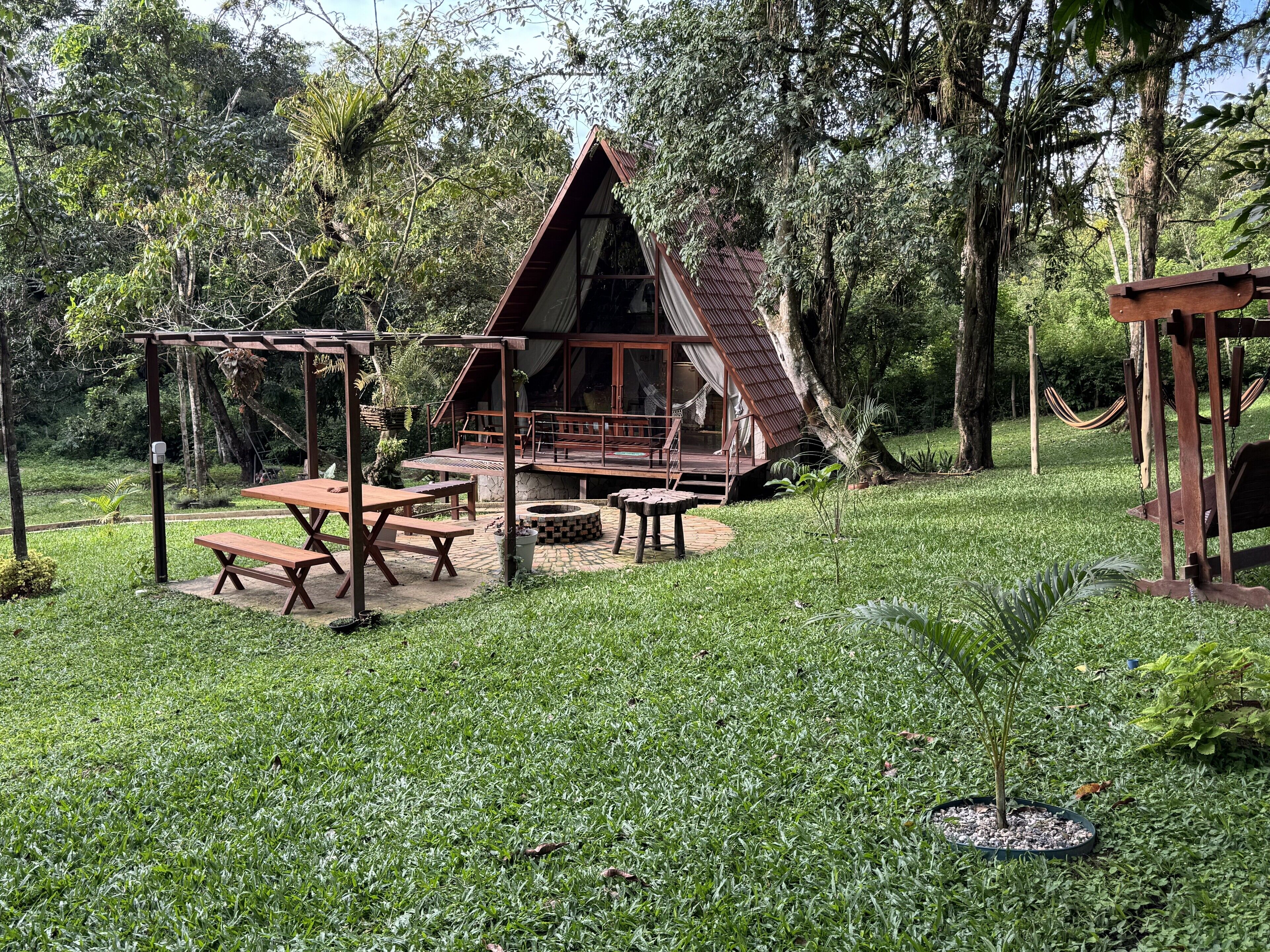 Una casetta di legno con veranda, tavoli da picnic e un'amaca.