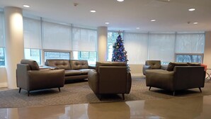 Un vestíbulo amplio con un gran árbol de Navidad, sofás de cuero y un piso de baldosas brillantes.