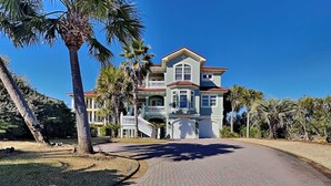 A large, two-story house with a red-tiled roof, a balcony, and a driveway leading to the entrance. - Legasea (Gulf Shores)