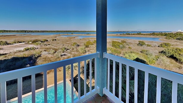 A balcony with a view of a pool and a coastal landscape. - Legasea (Gulf Shores)