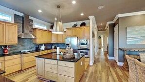 A spacious kitchen with wooden cabinets, a central island, and modern appliances. - Legasea (Gulf Shores)