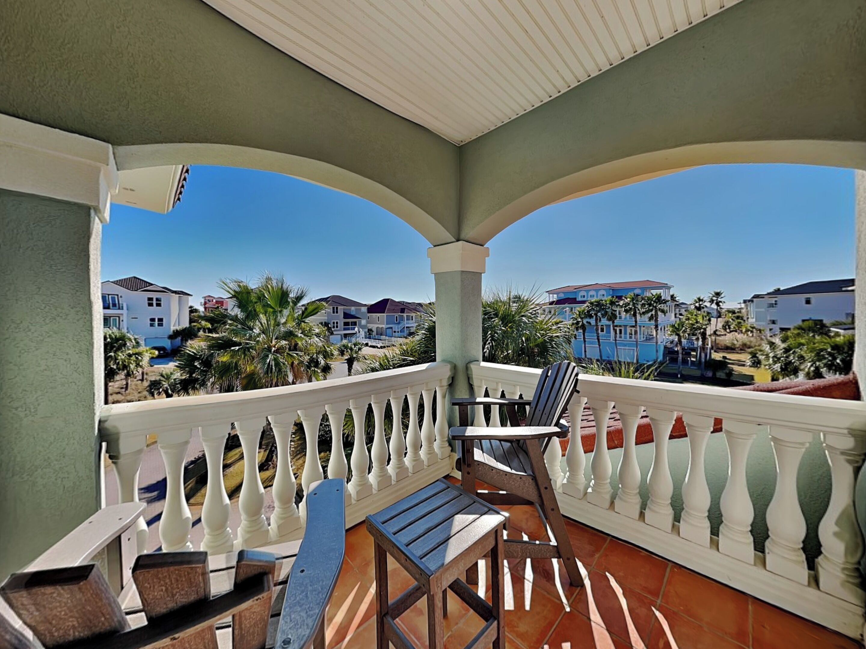 A balcony with a view of a resort area, including houses and palm trees.