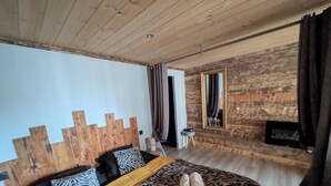 A bedroom with a wooden headboard, a zebra-patterned bedspread, and a small bedside table with a lamp. - La Darbella (Dole)