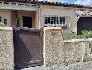 A gated entrance with a number '23' on the wall, a window with metal bars, and a tiled roof. - A warm and cozy home just 5 minutes from the city of Carcassonne. Quiet surroundings (CAZILHAC)
