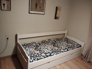 A small, single-bed room with a wooden frame, a floral bedspread, and a power outlet on the wall. - A warm and cozy home just 5 minutes from the city of Carcassonne. Quiet surroundings (CAZILHAC)