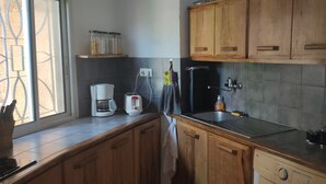 Une cuisine avec des meubles de rangement en bois, une machine à café, un grille-pain, un évier et un réfrigérateur.