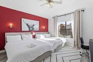 A hotel room with two beds, a ceiling fan, a large window with curtains, and a painting on the wall. - SW Houston 3BR Sleeps 10 | 2 Living Areas (Houston)