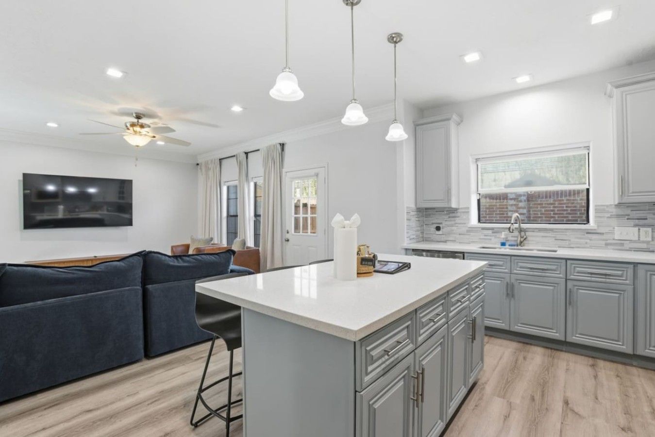 A modern kitchen with a central island, grey cabinetry, and pendant lighting.