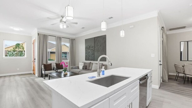 A modern kitchen with a large island, pendant lighting, and a view to the outside. - SW Houston 2BR | King Beds, Pets Welcome (Houston)