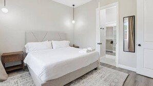 A modern bedroom with a large bed, bedside tables, a wardrobe, and a walk-in closet. - SW Houston 2BR | King Beds, Pets Welcome (Houston)