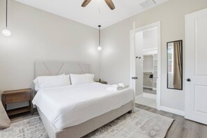 Une chambre à coucher moderne avec un grand lit, des tables de chevet, une armoire et un dressing.