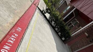 A concrete pathway with a yellow line, adjacent to a red-painted area marked 'NO PARKING.'